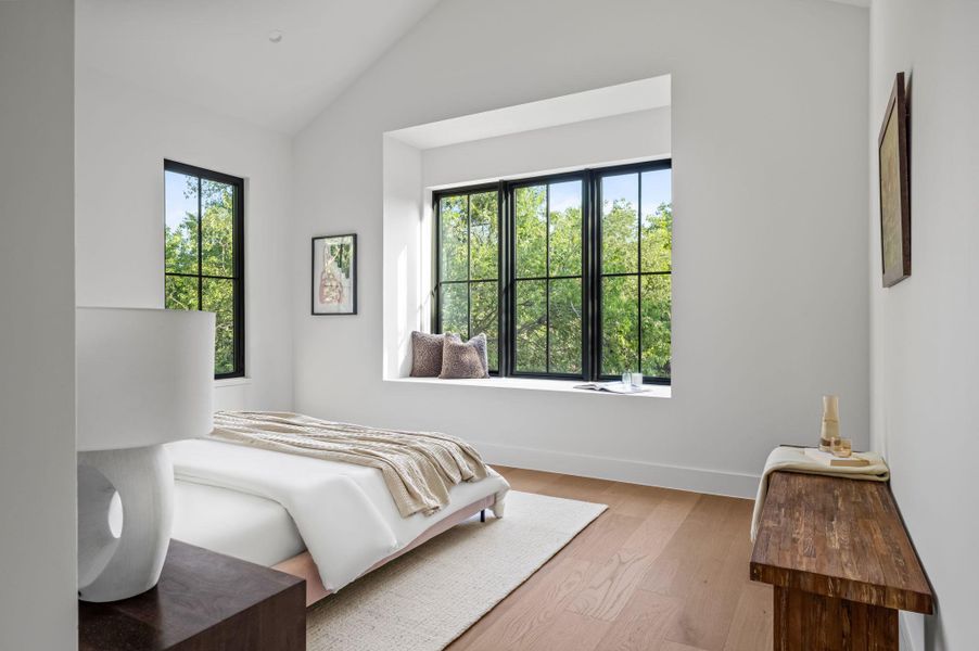 Hardwood floors and tall ceilings define this peaceful bedroom retreat, featuring a deep window seat with verdant views.