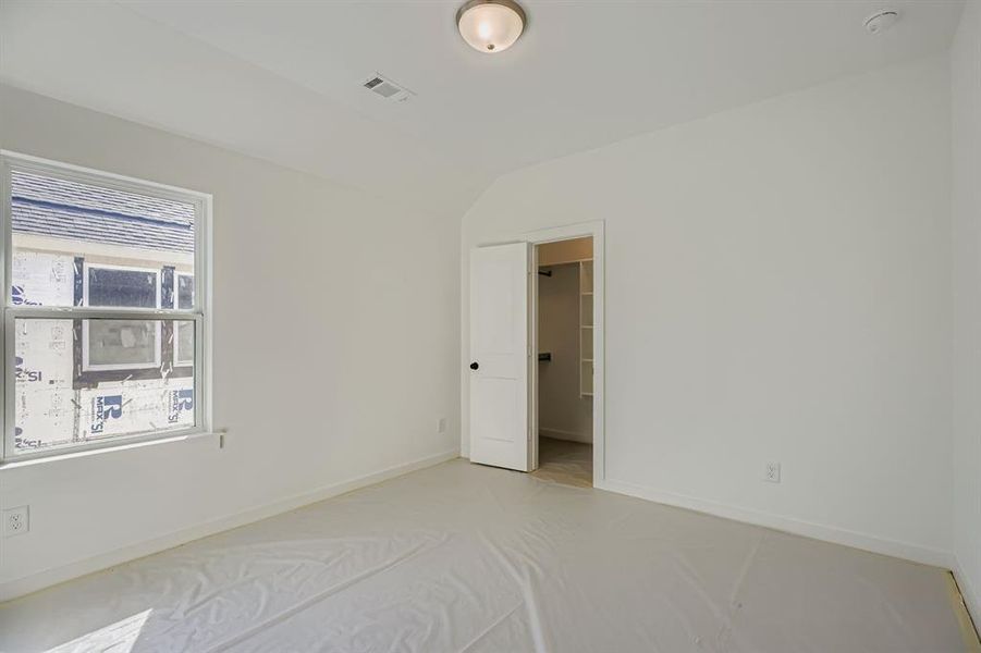 Unfurnished bedroom featuring vaulted ceiling and a walk in closet Unfurnished bedroom featuring vaulted ceiling and a walk in closet