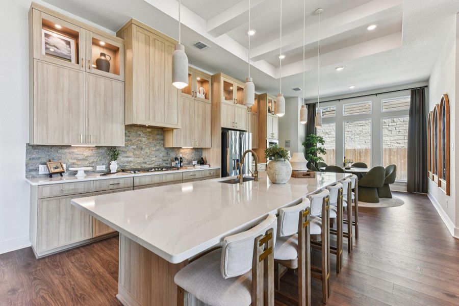 Warm wood cabinetry and stone accents complement a central island under a coffered ceiling.