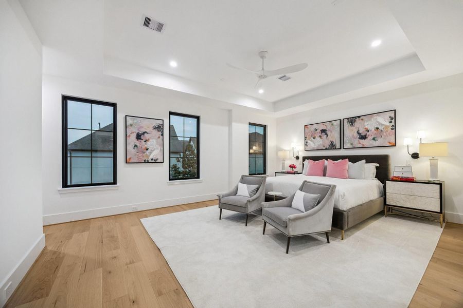 The serene bedroom is designed as a calm, light-filled retreat that blends modern simplicity with soft, inviting warmth. Architectural details such as the coffered ceiling and modern ceiling fan add dimension and functionality without overwhelming the space. Clean lines, reading lights, and warm woods, complete this beautiful room. There is also a coffee bar, not shown in the photo.