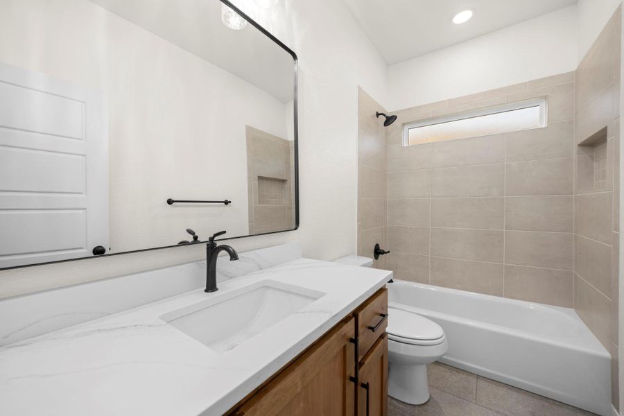 A well-appointed bathroom featuring a clean vanity, modern fixtures, and tiled shower.