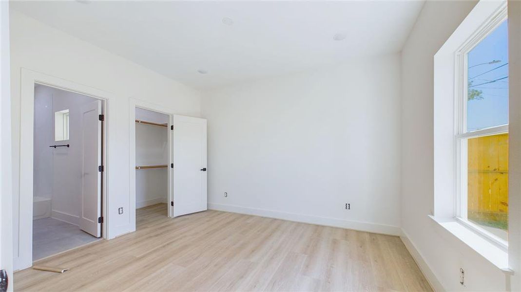 Alternate view of the first-floor bedroom. The spacious room offers wood-look LVP flooring, recessed lighting, and a large window that fills the room with natural light.