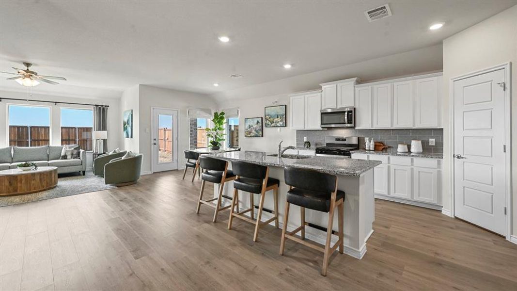Kitchen featuring white cabinetry, a breakfast bar, tasteful backsplash, open floor plan, and recessed lighting