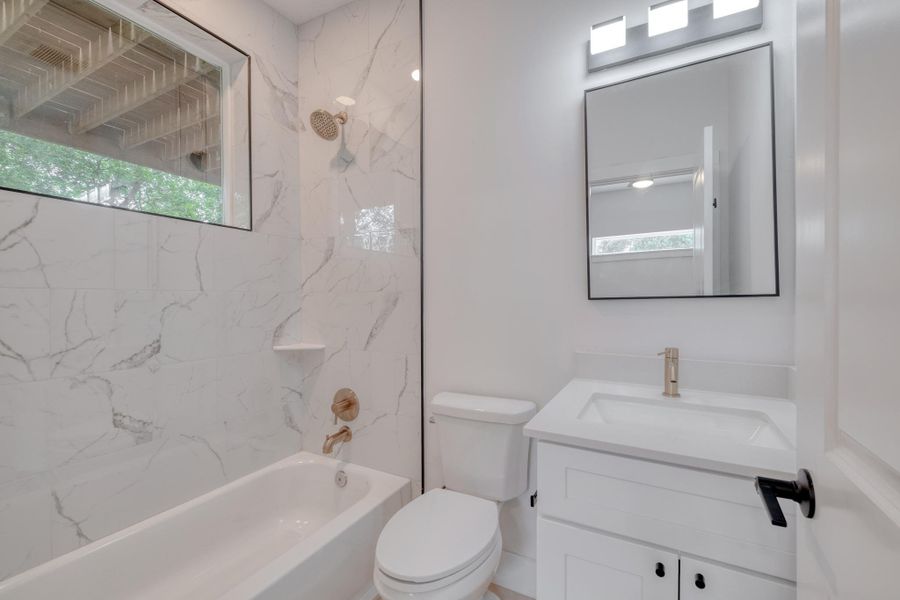 A well-lit bathroom features a shower-tub combination with elegant tile and a modern vanity. A well-lit bathroom features a shower-tub combination with elegant tile and a modern vanity.