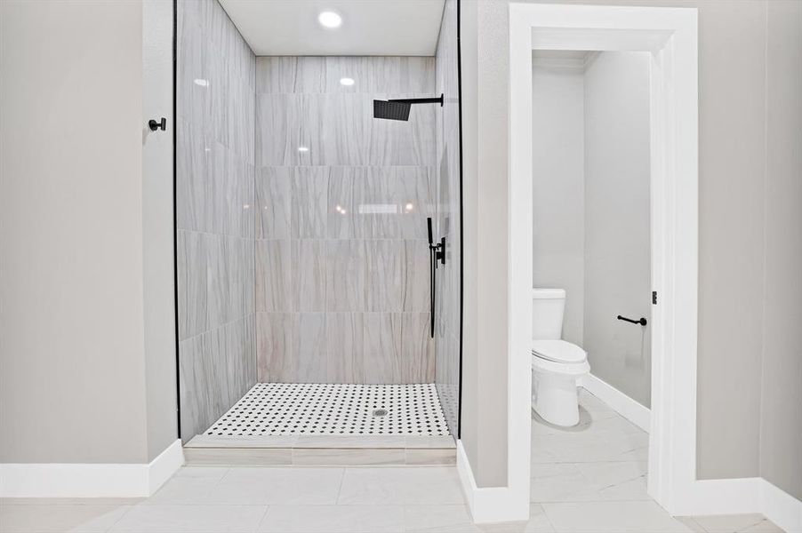 Bathroom featuring tiled shower and toilet