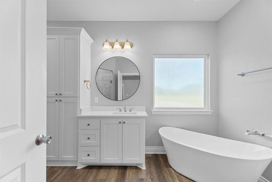 Full bath with vanity, a freestanding tub, and dark wood-style flooring