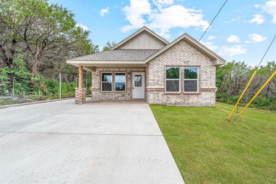 View of front facade featuring board and batten siding, brick siding, a front lawn, concrete driveway, and a shingled roof View of front facade featuring board and batten siding, brick siding, a front lawn, concrete driveway, and a shingled roof