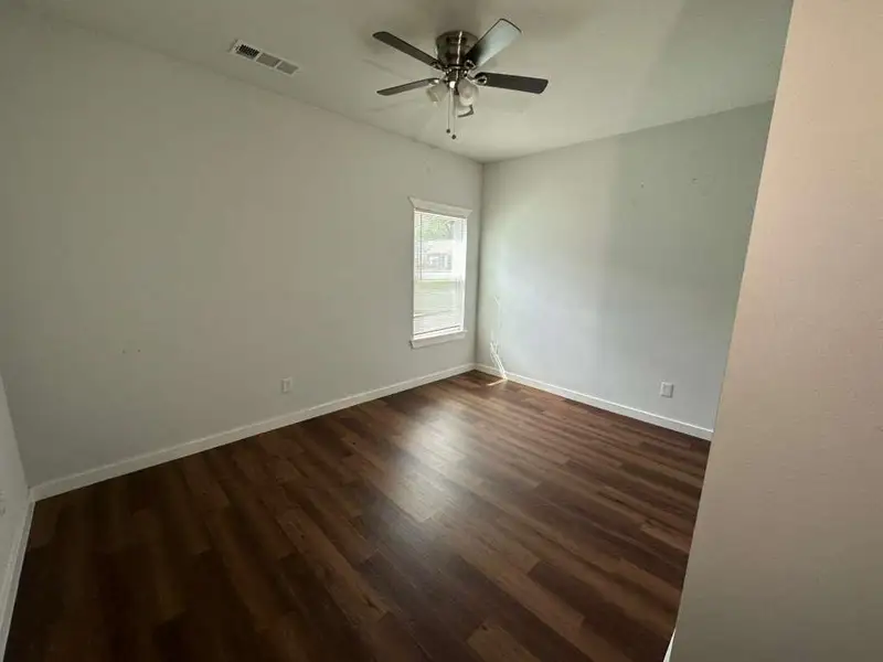 Spare room featuring dark wood-style flooring and ceiling fan