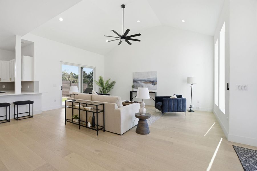 Living room featuring light wood-style flooring, ceiling fan, recessed lighting, and lofted ceiling