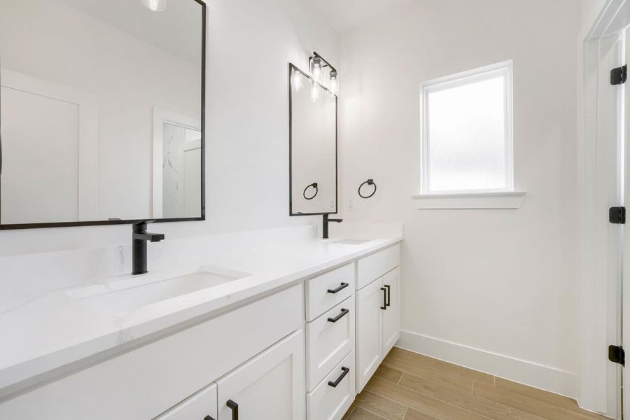 Double vanities with sleek black hardware elevate this bright, functional primary bathroom.