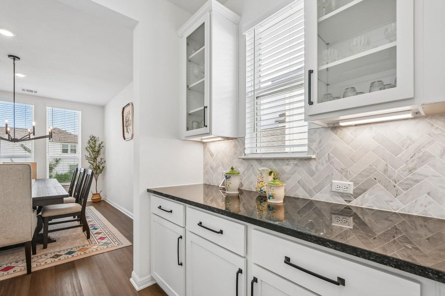 Elegant herringbone tile backsplash accents a sleek countertop, providing a perfect complement to the dining area's natural light.