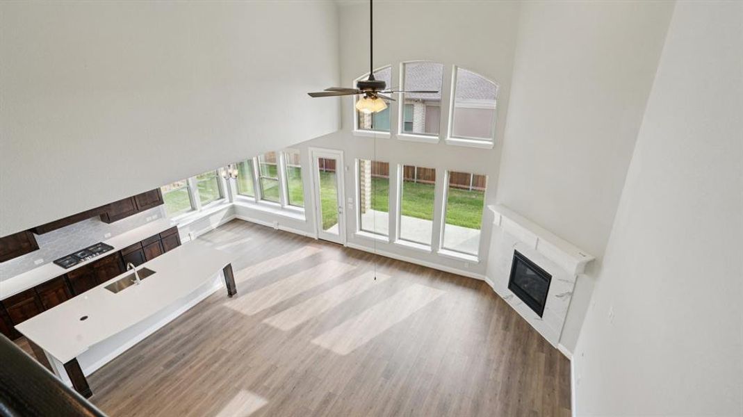 Unfurnished living room with a high ceiling, a glass covered fireplace, light wood finished floors, and a ceiling fan Unfurnished living room with a high ceiling, a glass covered fireplace, light wood finished floors, and a ceiling fan