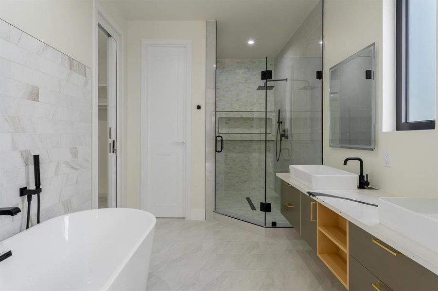 Full bath with a soaking tub, a shower stall, double vanity, and a closet