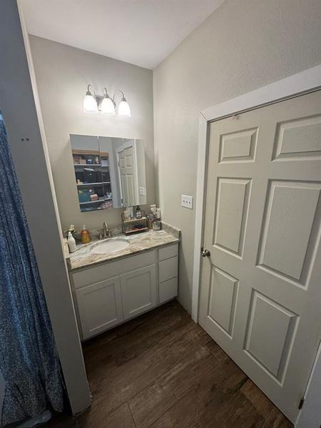 Bathroom with vanity, dark wood-type flooring, and a shower with shower curtain Bathroom with vanity, dark wood-type flooring, and a shower with shower curtain