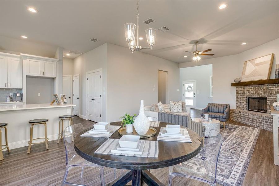 Dining space featuring recessed lighting, wood finished floors, a ceiling fan, and a brick fireplace