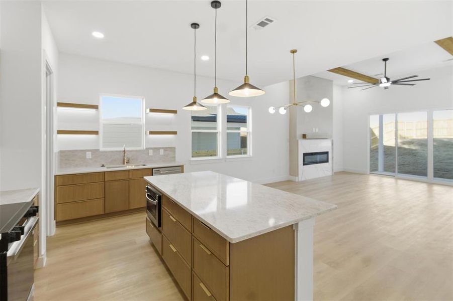 Kitchen featuring open shelves, light wood-style flooring, hanging light fixtures, light stone countertops, and ceiling fan