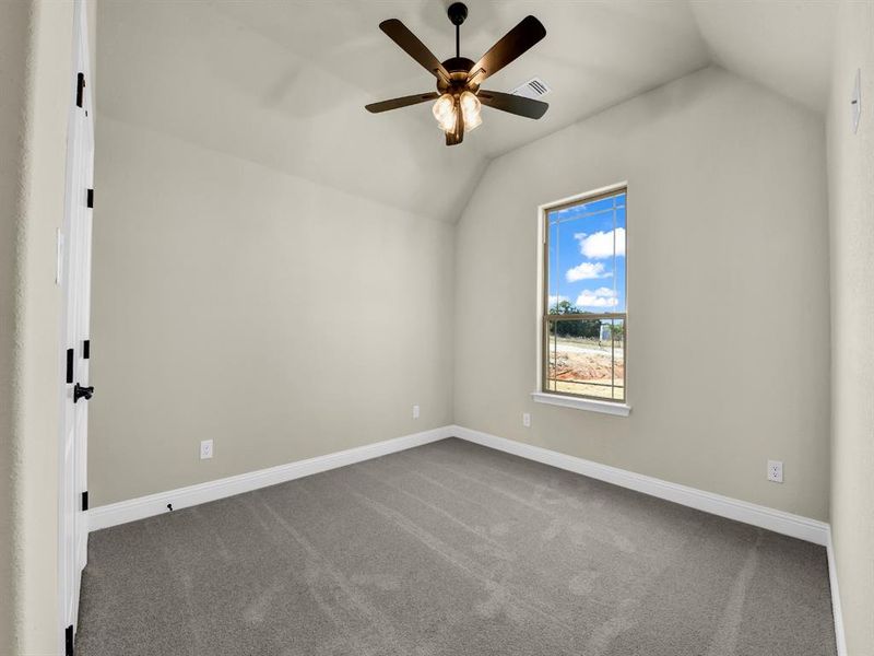 Carpeted spare room with vaulted ceiling and ceiling fan