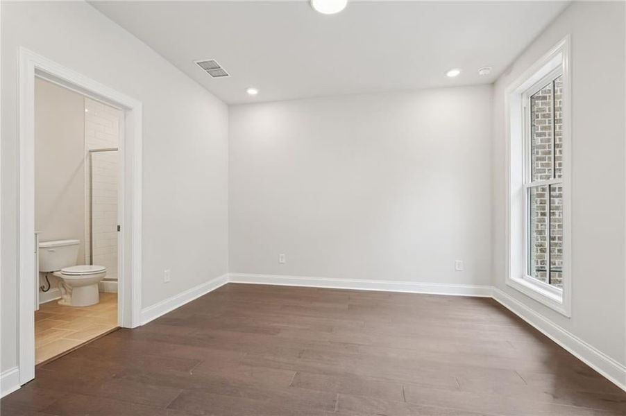Unfurnished bedroom featuring dark wood finished floors, recessed lighting, and ensuite bath