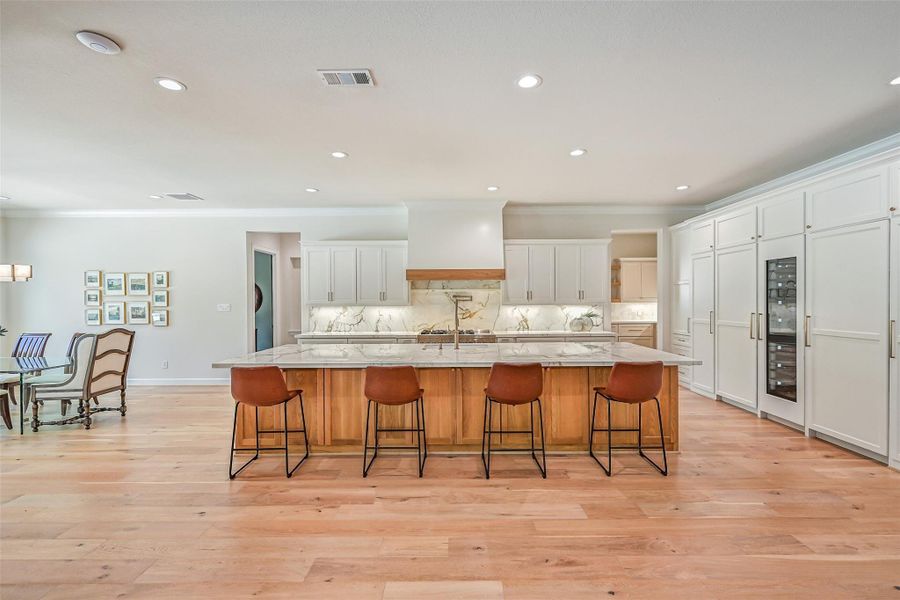 Showstopping kitchen boasts an enormous wood island topped with dramatic Calacatta Macchia Vecchia porcelain, extensive custom cabinetry, paneled refrigerator & freezer, built-in wine refrigerator and an impressive professional-style gas range.