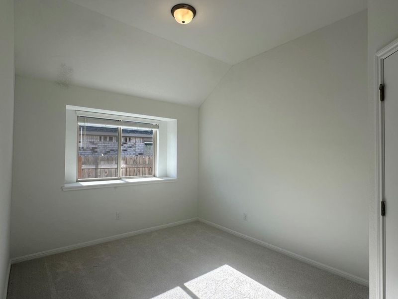 Empty room featuring vaulted ceiling and carpet flooring Empty room featuring vaulted ceiling and carpet flooring
