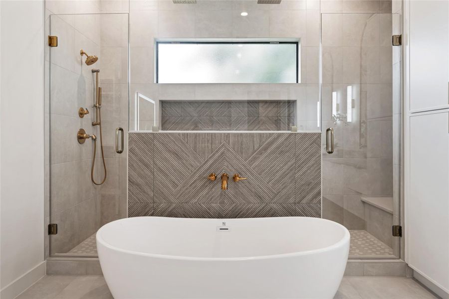 Decorative textured tile accents the huge shower with dual rain shower ceiling heads and convenient bench seating on one side, as well as a traditional shower area on the other side.  There is also a stunning freestanding tub for ultimate relaxation.