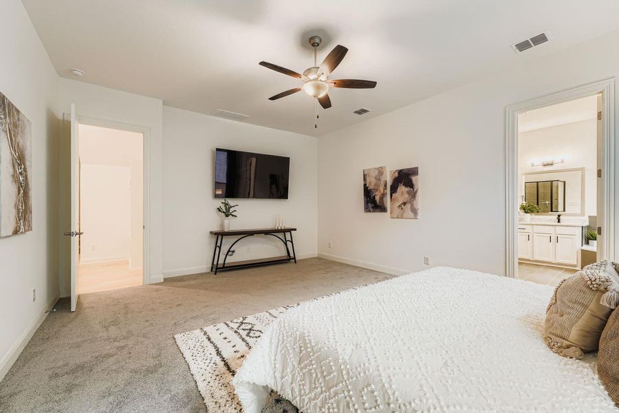 Bedroom featuring light carpet, ensuite bath, and ceiling fan Bedroom featuring light carpet, ensuite bath, and ceiling fan