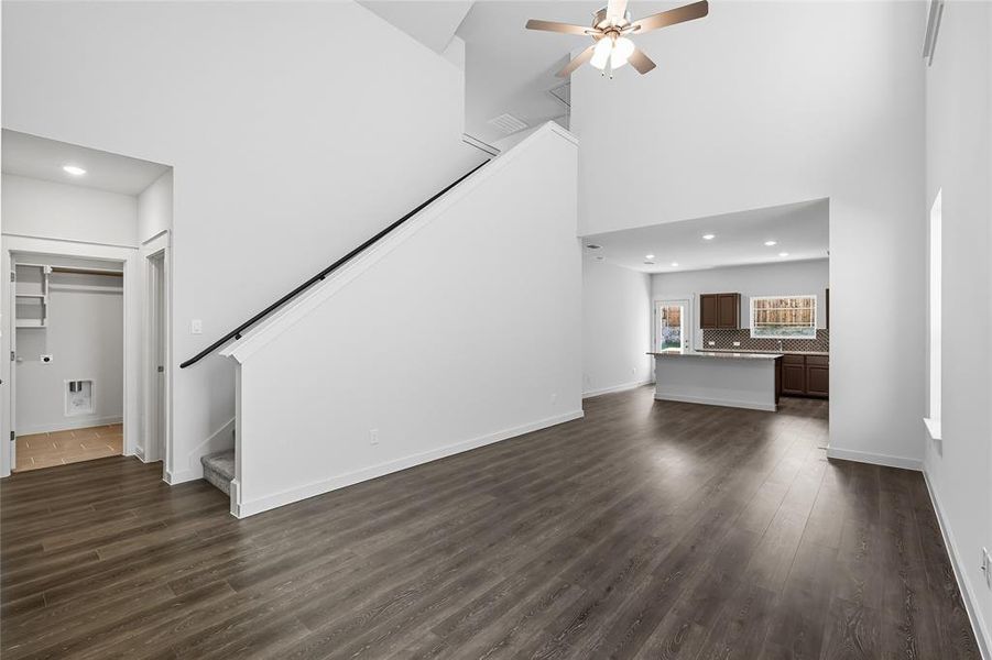 Unfurnished living room featuring recessed lighting, stairs, dark wood-type flooring, a towering ceiling, and ceiling fan Unfurnished living room featuring recessed lighting, stairs, dark wood-type flooring, a towering ceiling, and ceiling fan