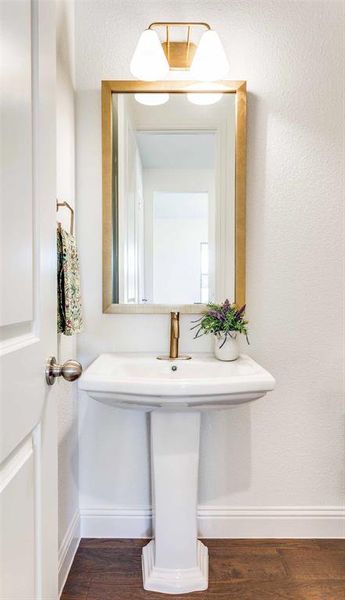 Bathroom featuring dark wood finished floors and a textured wall Bathroom featuring dark wood finished floors and a textured wall