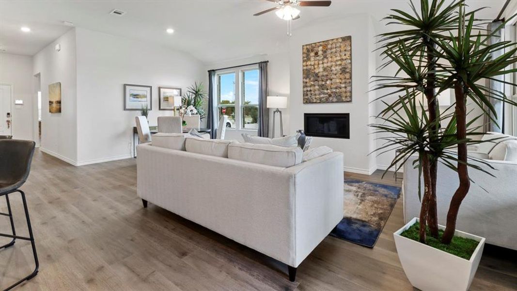 Living room featuring a glass covered fireplace, wood finished floors, ceiling fan, lofted ceiling, and recessed lighting