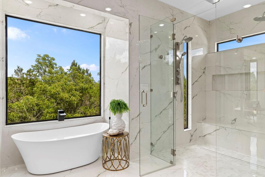 Full bathroom featuring stone wall, a freestanding tub, a marble finish shower, and marble tiled floors