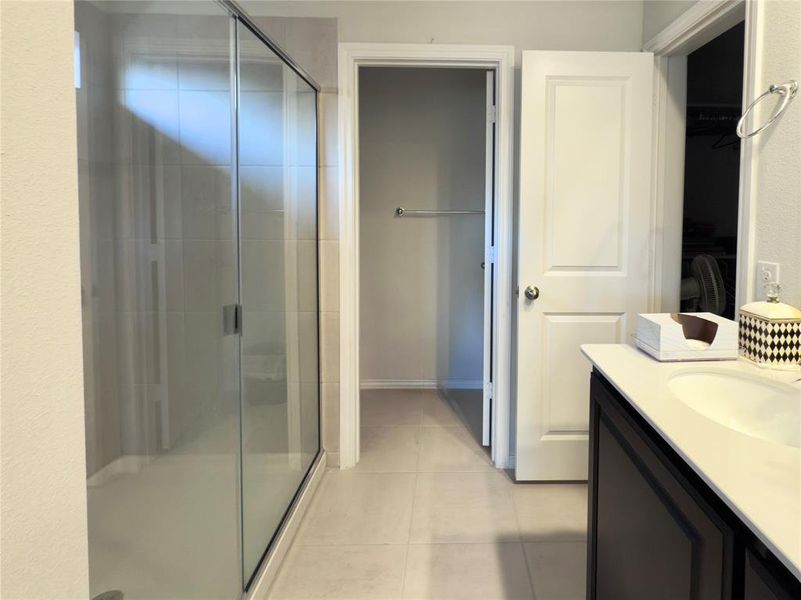 Bathroom featuring a shower stall, vanity, and light tile patterned floors Bathroom featuring a shower stall, vanity, and light tile patterned floors