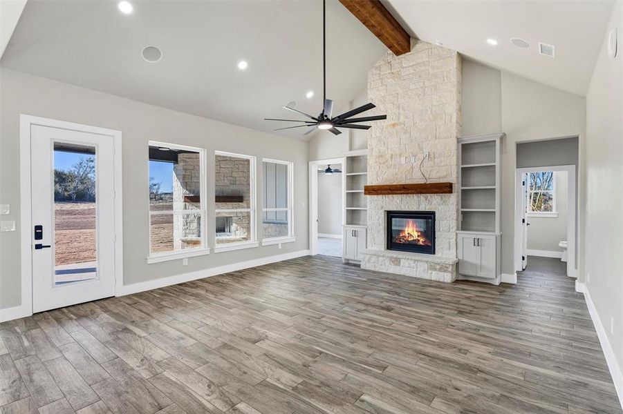 Unfurnished living room featuring lofted ceiling with beams, ceiling fan, hardwood / wood-style flooring, and a fireplace