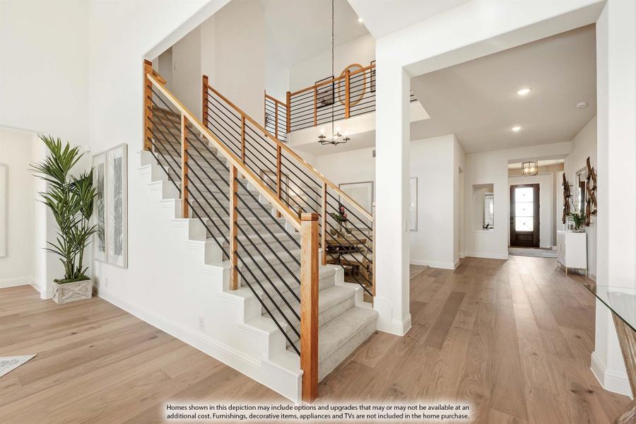 Open foyer with wood and metal staircase, hardwood floors, and hallway leading to front door Open foyer with wood and metal staircase, hardwood floors, and hallway leading to front door