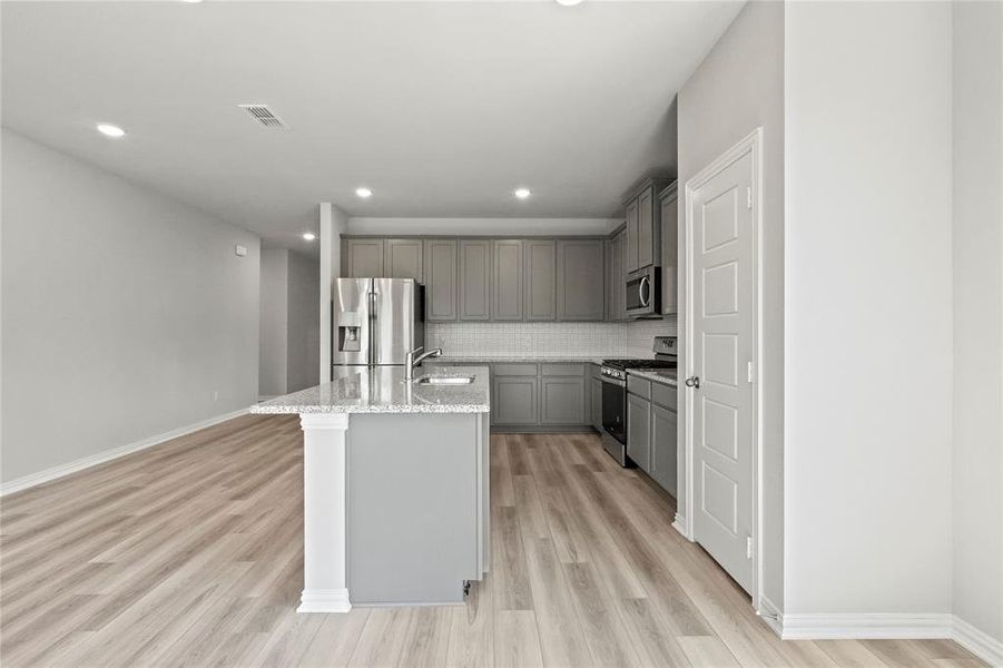 Kitchen featuring stainless steel appliances, tasteful backsplash, and light wood-type flooring