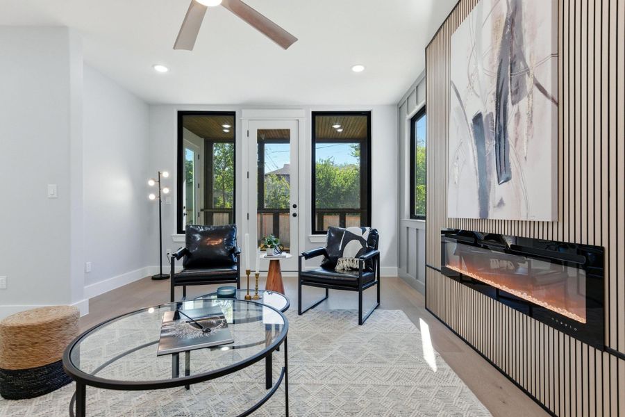 Living area featuring a glass covered fireplace, light wood-type flooring, recessed lighting, and a ceiling fan Living area featuring a glass covered fireplace, light wood-type flooring, recessed lighting, and a ceiling fan