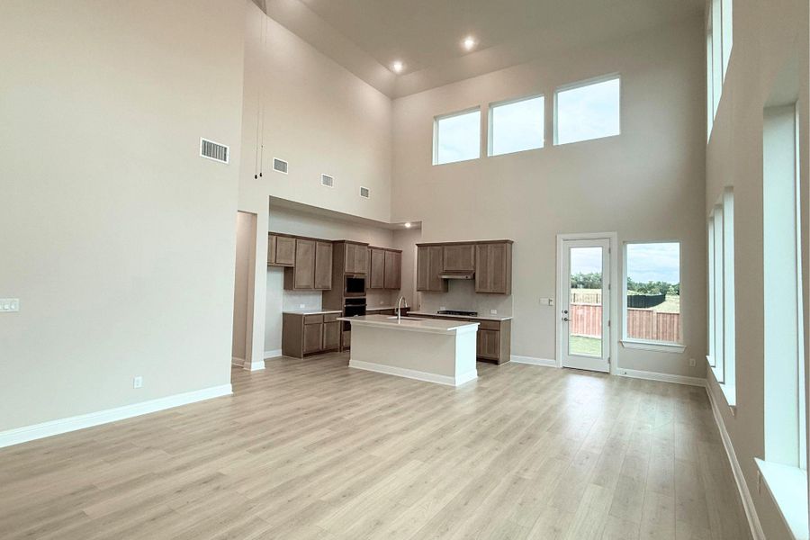 A spacious, open-concept living area with soaring ceilings and abundant natural illumination, seamlessly connects to a modern kitchen. A spacious, open-concept living area with soaring ceilings and abundant natural illumination, seamlessly connects to a modern kitchen.