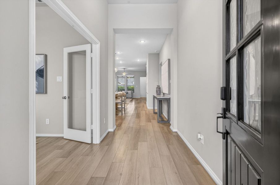 This photo shows a welcoming entryway with light wood flooring, neutral walls, and a view leading to a well-lit open-concept home. A glass door opens to a dedicated office, adding versatility and light. This photo shows a welcoming entryway with light wood flooring, neutral walls, and a view leading to a well-lit open-concept home. A glass door opens to a dedicated office, adding versatility and light.
