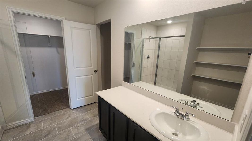 Bathroom vanity featuring a single basin sink, chrome faucet, and expansive wall-mounted mirror Bathroom vanity featuring a single basin sink, chrome faucet, and expansive wall-mounted mirror