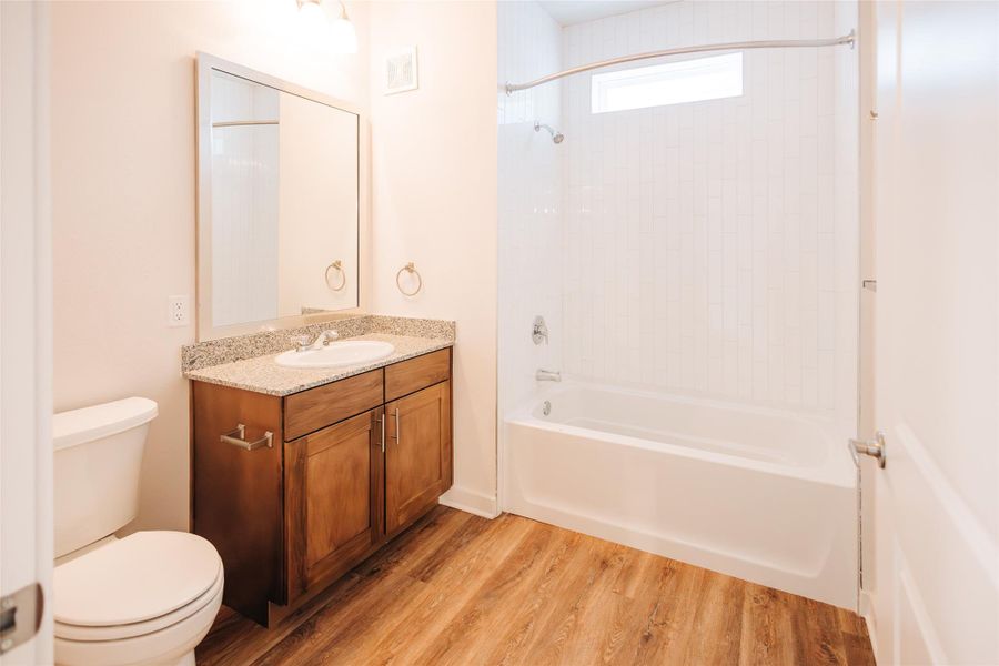 Bathroom with toilet, shower / washtub combination, wood finished floors, and vanity