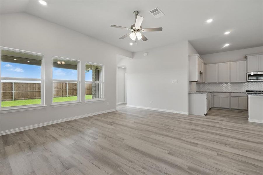 Unfurnished living room featuring a ceiling fan, recessed lighting, light wood finished floors, lofted ceiling, and baseboards Unfurnished living room featuring a ceiling fan, recessed lighting, light wood finished floors, lofted ceiling, and baseboards