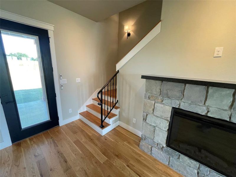 Wood-finish flooring throughout, with a stacked stone fireplace featuring a dark mantelpiece