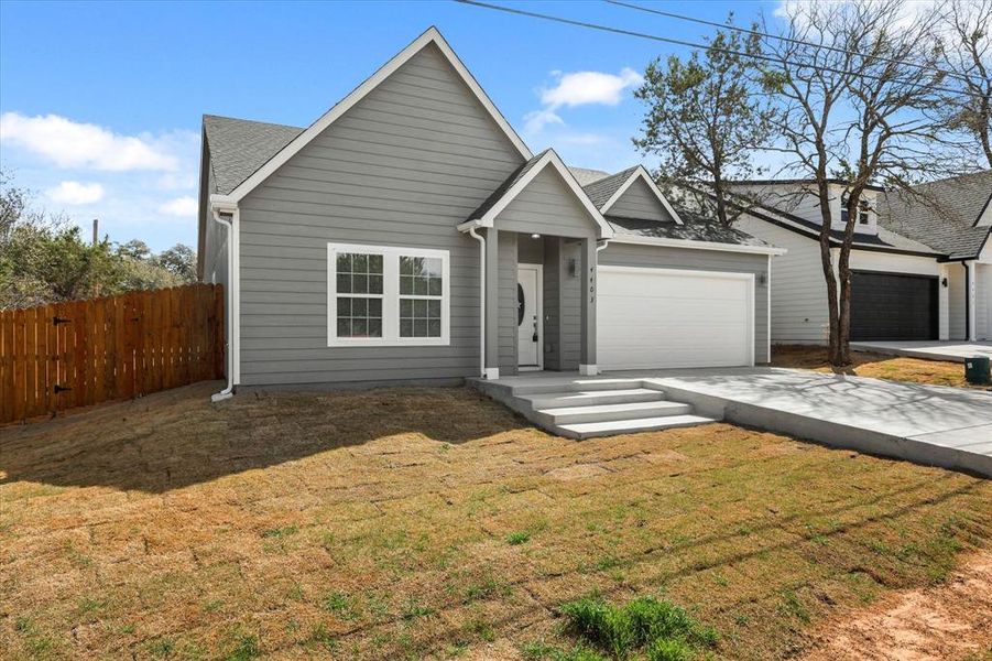 View of front of home featuring a shingled roof, a front lawn, fence, concrete driveway, and a garage