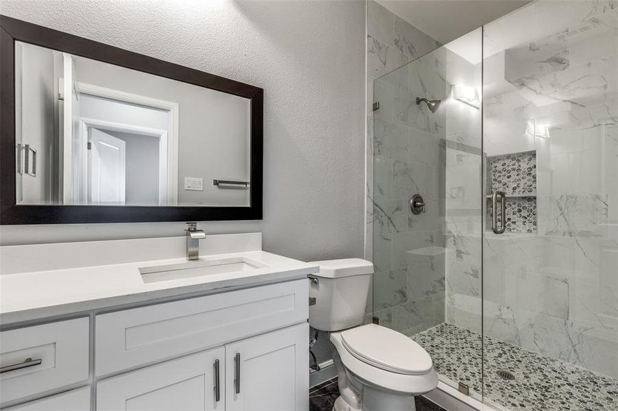 Bathroom featuring vanity, an enclosed shower, and toilet