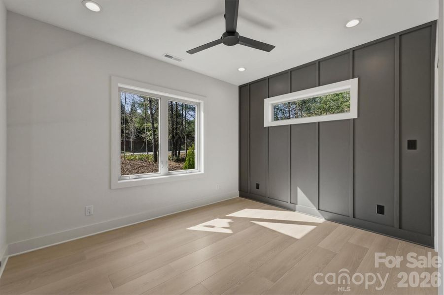 To the left of the front door, there is a guest bedroom, Suite 2.. There is a Minka-Aire ceiling fan, and a feature wall with a transom window over the bedspace. To the left of the front door, there is a guest bedroom, Suite 2.. There is a Minka-Aire ceiling fan, and a feature wall with a transom window over the bedspace.