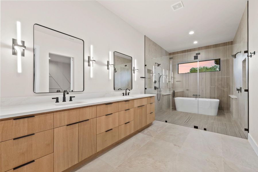 Indulge in a spa-like retreat with this contemporary bathroom featuring a dual vanity, sleek mirrors, and a spacious glass-enclosed shower with a freestanding soaking tub.
