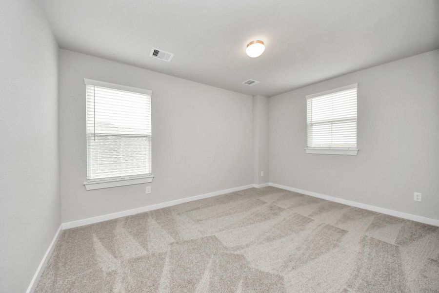Secondary bedroom features plush carpeting, large windows that let in plenty of naturallight, bright paint, and spacious closets.