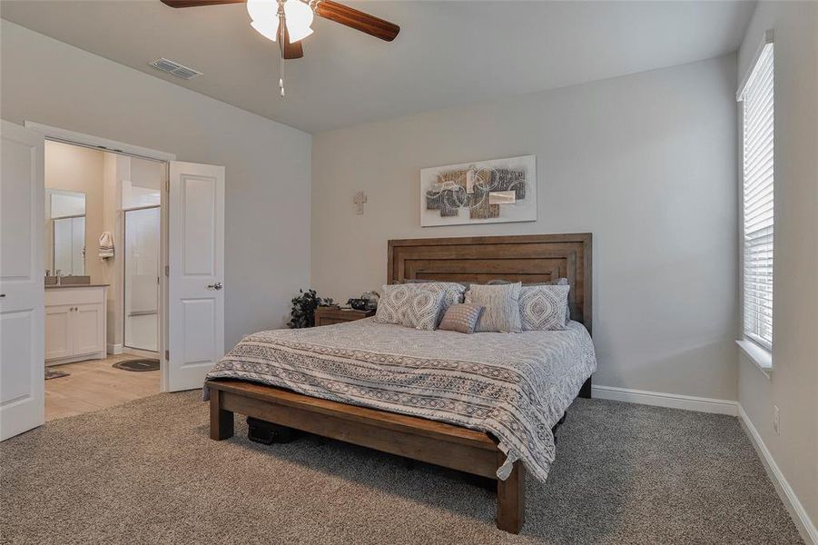 Bedroom with light carpet, connected bathroom, and a ceiling fan Bedroom with light carpet, connected bathroom, and a ceiling fan