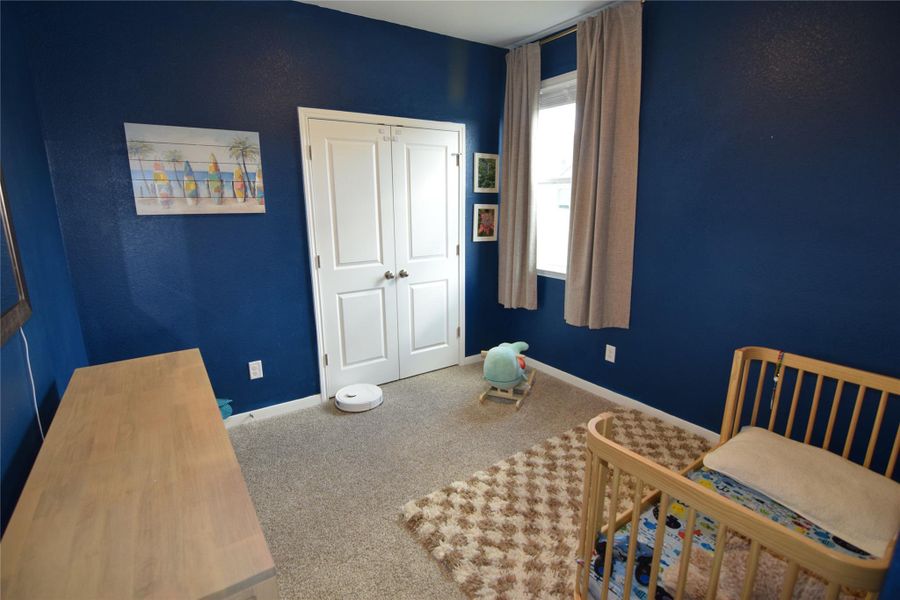 A single window illuminates this cozy bedroom lined with soft carpet underfoot.