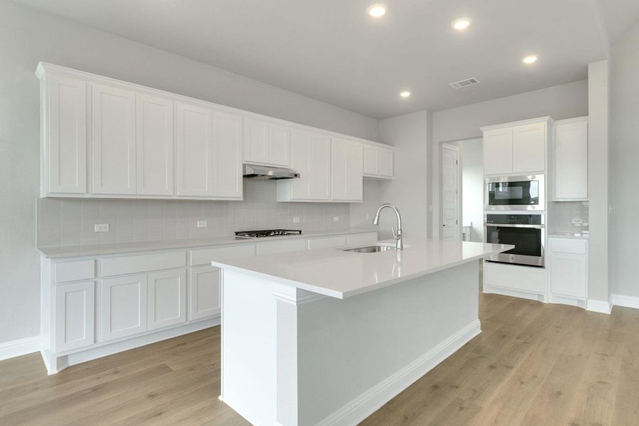 Kitchen with backsplash, visible vents, appliances with stainless steel finishes, a sink, and under cabinet range hood