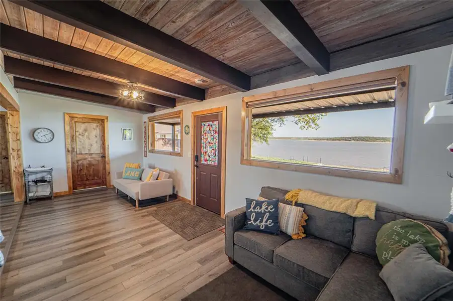 Living room featuring wood finished floors, a water view, and a wooden ceiling with exposed beams Living room featuring wood finished floors, a water view, and a wooden ceiling with exposed beams